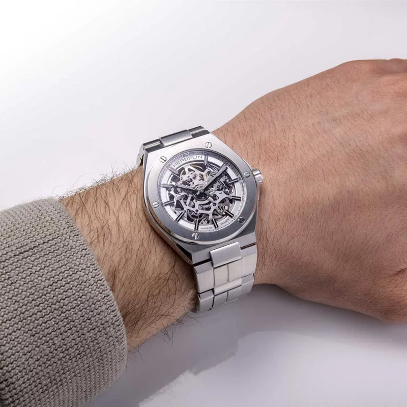 Réf : 1845BSQ12  Au design identitaire des années 70, la collection Cap Camarat s’agrandit avec ce nouveau modèle automatique. Dévoilant sans complexe sa beauté intérieure grâce à son cadran transparent, cette montre sport chic est éditée en série limitée à 500 exemplaires. Le bracelet intégré fait corps avec la boite, tous les deux en acier inoxydable donnent un esprit moderne à Cap Camarat Squelette. Cette montre Herbelin est à la fois sportive et moderne.